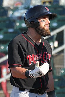 A man wearing a black batting helmet and black baseball jersey with "Music City" written across the chest in red lettering