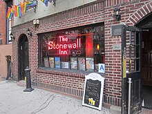 The Stonewall Inn's storefront window, which contains various posters and a sign with the bar's name