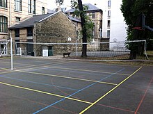 Photographie des terrains de sport du lycée Molière, et, au fond, une des façades du lycée et des bâtiments annexes.