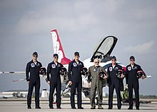 Photographie en couleur d'Aldrin et de pilotes de la patrouille acrobatique de l'armée de l'air américaine posant devant un de leur avion.