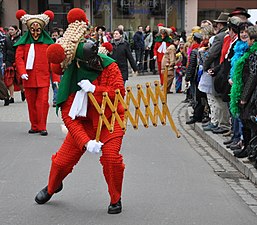 Un streckschere, en anglais également appelé lazy tongs, avec une structure articulée comme un pantographe, est un objet utilisé par les participants pour taquiner les spectateurs ou attraper leurs casquettes et leurs chapeaux, et parfois pour distribuer des bonbons et autres petits cadeaux.