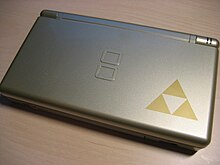 Une console rectangulaire carrée de couleur dorée, où une figure géométrique composée de plusieurs triangles emboîtés est visible.