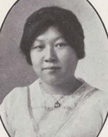 A young Chinese woman, her dark hair in an updo, wearing a light-colored blouse with ribbon and lace trim