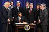 President Obama signs law into effect, on December 17, 2010, as members of Congress and others look on.