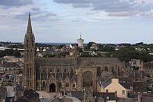 Photographie de la façade sud de l'église prise depuis un point élevé de la chapelle du Kreisker. On voit les flèches à gauche, puis la nef avec le porche, le transept sud et le chevet