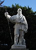 A marble statue showing a man in polar clothing holding a rod, in front of trees