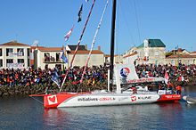 Voilier blanc et rouge, vu de profil, avançant dans le chenal des Sables-d'Olonne.