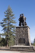 Photograph of a memorial at the Donner Camp, a set of bronze figures, woman, man, and child, atop a tall stone plinth.