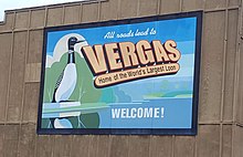 brightly painted sign reading "all roads lead to Vergas, home of the world's largest loon. Welcome!"