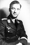 Black-and-white photo of a smiling, sitting man in military uniform.