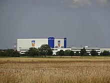 A mostly white large building styled after a crate of Capri-Sun: It has blue towers at two corners with "Capri-Sun" on both outer sides at their peaks; midway along both visible sides, there is an image of an Orange-flavor Capri-Sun pouch.