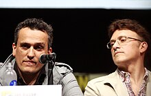 Joe and Anthony Russo, seated; Joe wears glasses, and Anthony is in front of a microphone.