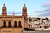 Au premier plan, sur la moitié gauche de la photographie, une partie de la façade du museo del Planchado ; en arrière-plan, sur la moitié droite, panorama d'habitations de Zacatecas.