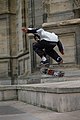 Un skater effectue un flip. Il est en l'air et a donné une impulsion avec le pied à son skateboard qui est en train d’effectuer seul une rotation.