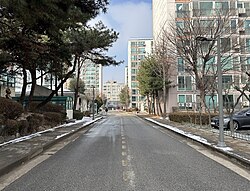 Inside the enclave. The buildings to the left and right are part of the enclave. The building at the end of the road is an unrelated commercial building (2024)