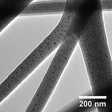 The image depicts fibers of roughly 100 nm size with tiny dots within.