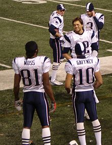 Tom Brady (no 12), de face, derrière Gaffney (no 10), au bord du terrain après son 50e touchdown de la saison.