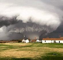 A photograph depicting a large, violent tornado; houses are evident in the foreground.