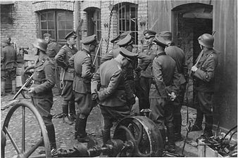 NARA copy #3, IPN copy #3 Discussing the evacuation of the factory The guard on the left is Josef Blösche. The photo depicts the Herman Brauer helm repair shop at Nalewki 28–38. 24 April 1943