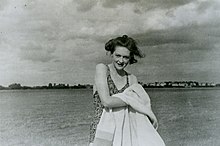 Photograph of a woman wearing a swimsuit, drying herself with a towel