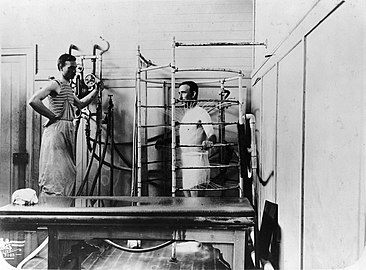 Photo d'un homme dans une douche à cage avec un employé réglant la machine.