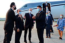 A group of people wearing COVID masks outside a small airplane