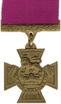 A bronze cross pattée bearing the crown of Saint Edward surmounted by a lion with the inscription 'FOR VALOUR'. A crimson ribbon is attached.