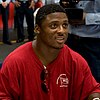 Headshot of Warrick Dunn sitting and signing autographs