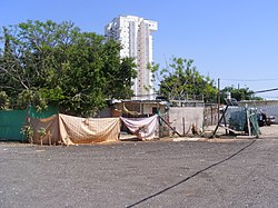 צריפים בשכונת הארגזים. מאחור ניתן לראות את בניין המגורים היחיד שהוקם על השטח המפונה בדרום השכונה על ידי הקבלן ישעיהו חכשורי