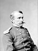 Head and torso portrait of a white man with a pointed mustache wearing a military jacket.