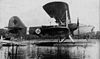 A 1930s-era biplane, marked with a Nazi swastika, resting on its floats on the water
