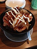 A bowl of Japanese rice topped with karaage chicken, soft-boiled egg, vegetables and topped with condiments