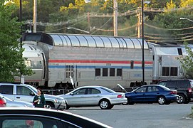 A stainless steel passenger dome rail car with red, white, and blue stripes of equal width on the side