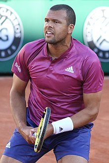 Tsonga in a red shirt looking into the camera.