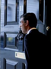 Sunak, facing away from the camera, framed by the door of 11 Downing Street.