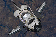 Discovery is approaching the International Space Station during STS-121. The payload in the shuttle's cargo compartment would be attached to the ISS later in the mission. The spaceship's unique 'teardrop' feature, consisting of several black tiles near the cockpit, is clearly visible.