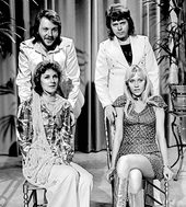 Black-and-white image of ABBA, with the male members standing while the female members sitting in front.