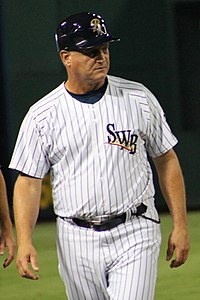 A man in a white baseball uniform with dark pinstripes