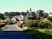 une vue générale d'un village s'étageant au flanc d'un coteau boisé avec un cours d'eau en premier plan