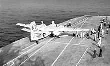 Black and white photograph of an aircraft on the deck of an aircraft carrier