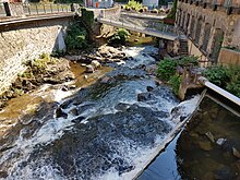 Photographie de la rivière Durolle prise devant l'usine du May. La photographie met en évidence le fait que son débit est relativement faible en été : les rochers sont très visibles.