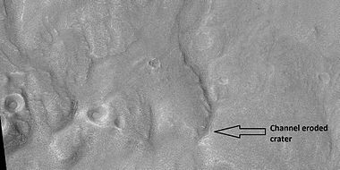 Channel that travels through part of a crater, as seen by HiRISE under HiWish program. The arrow shows a crater that was eroded by the channel. Note: this is an enlargement of a previous image.