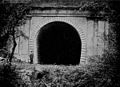 View of the abandoned tunnel, ca. 1911. A man stands to the left for a height comparison.