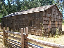 A shingled log cabin alongside a split rail fence is the oldest structure on the Big Sur coast.