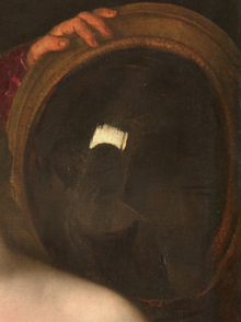 Détail d’une peinture montrant l’épaule d’une femme (au premier plan, à gauche) et, en arrière-plan, un miroir tenue par une main (en haut, à gauche du bord) et dont la glace occupe presque la totalité de la vue. Dans le miroir se reflètent le dos de la femme et l'intérieur très peu éclairé de l'habitation.