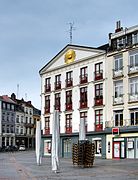 Photo de l'immeuble blanc de l'ancienne enseigne du Beau Soleil, composé de trois lignes de cinq fenêtres, avec en arrière plan la rue Esquermoise.