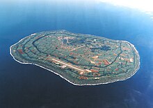 Vue aérienne couleur d'une île, dans une étendue d'eau bleue.