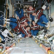 Seven astronauts in matching clothes floating in Spacelab