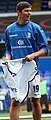 A dark-haired white man wearing a blue training top and white shorts