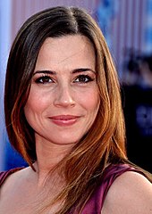 Cardellini wearing a violet sleeveless wrap, hair in a shoulder-length feather cut